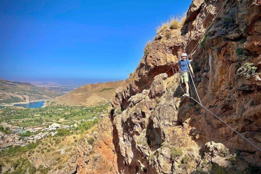 A person on a rope bridge over a canyon with a valley below. 4