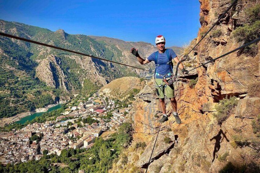 A person rappelling down a rocky cliff with a town in the valley below. 5