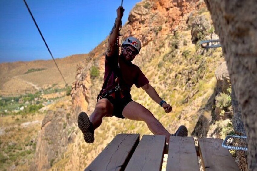 A person zip-lining over a rocky cliff with a mountainous landscape in the background. 2