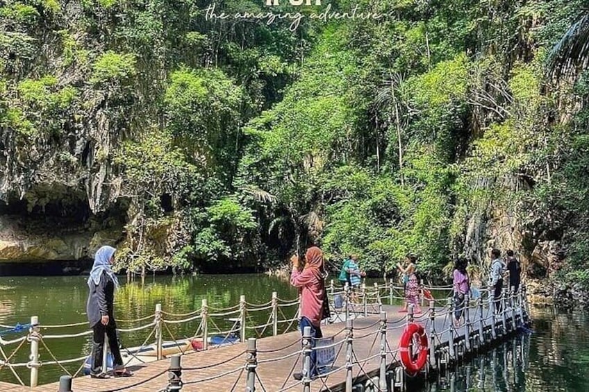 A wooden dock extending over a calm river, surrounded by lush greenery and rocky cliffs. 2
