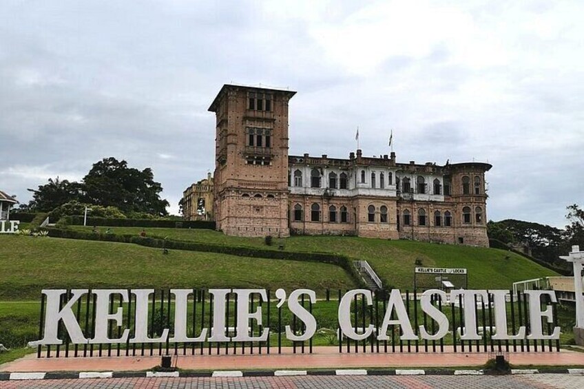 Kellie's Castle, a large brick building with a tower, surrounded by a well-maintained lawn and a sign in the foreground. 4