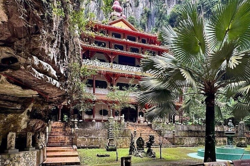 A traditional multi-tiered building with a red roof, surrounded by lush greenery and a rocky cliff. 3
