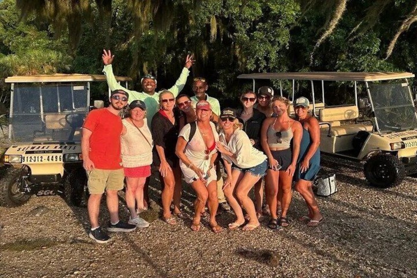 A group of people posing in front of a golf cart. 4