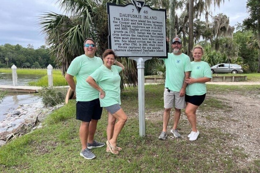 Four people standing in front of a historical marker sign. 2