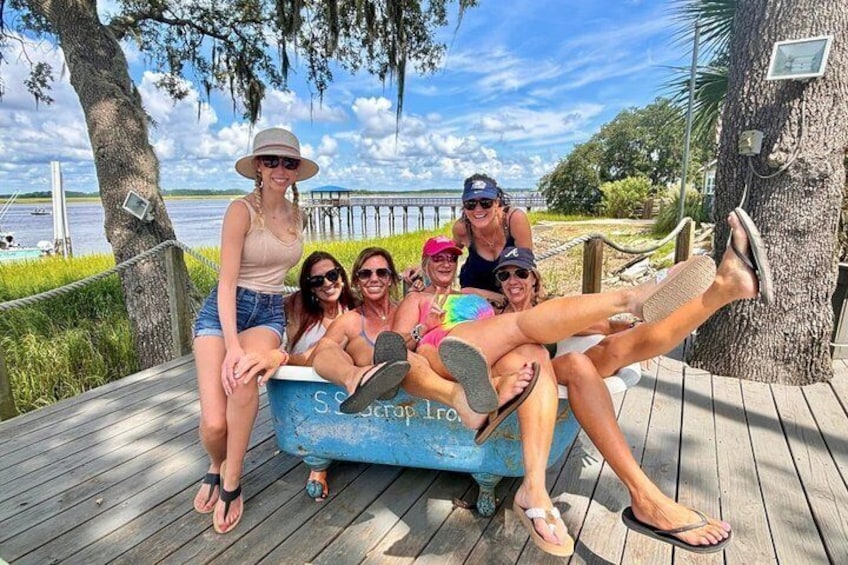 A group of people relaxing on a wooden deck by a body of water. 1