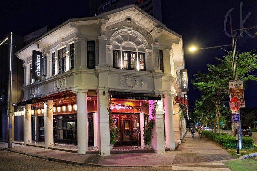Un edificio luminoso con facciata in stile classico, insegne illuminate e marciapiede di fronte. 2