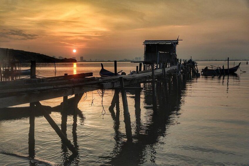 Un tramonto su un'acqua calma, con un molo che si protende verso l'acqua, imbarcazioni ormeggiate al molo e un piccolo edificio sul molo. 5