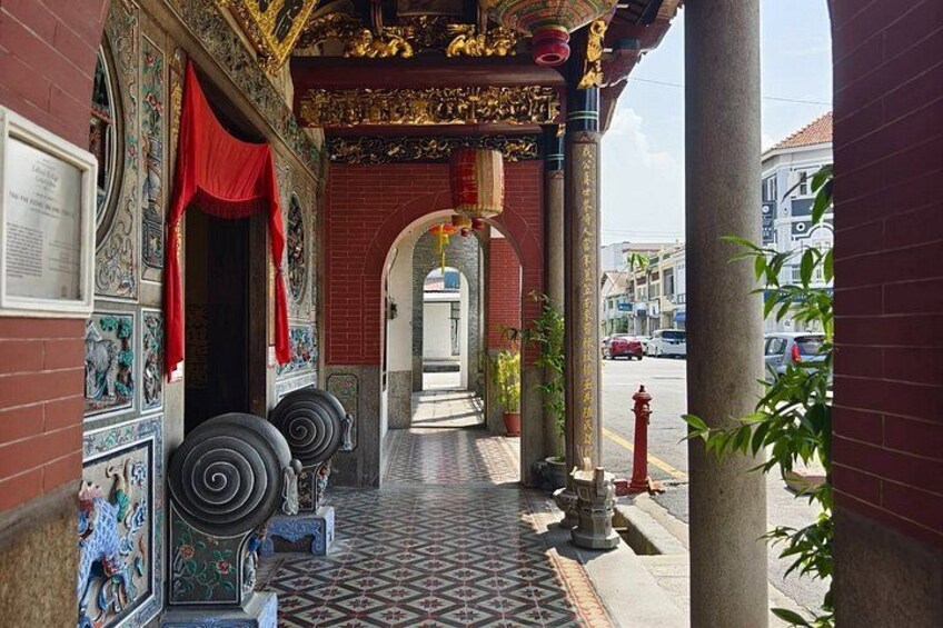 Un porticato con elaborate decorazioni in piastrelle, tende rosse e un idrante rosso. 3