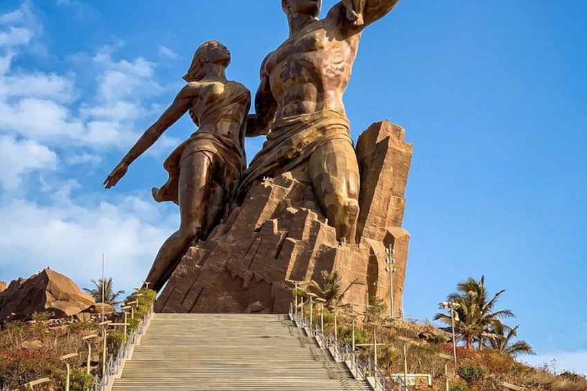 A large stone statue of a man and woman on a hill with a staircase leading up to it. 3