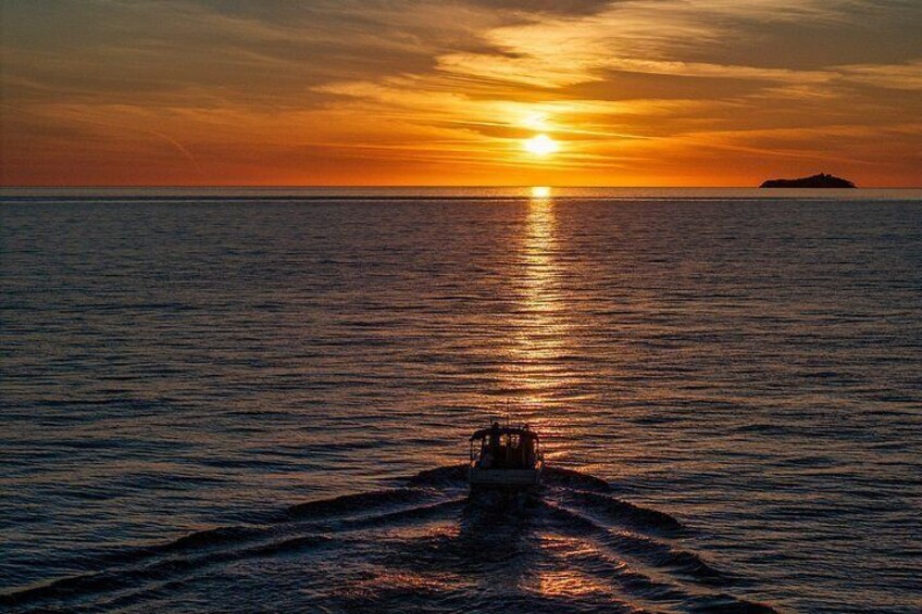 A boat on calm water with a sunset in the background. 2