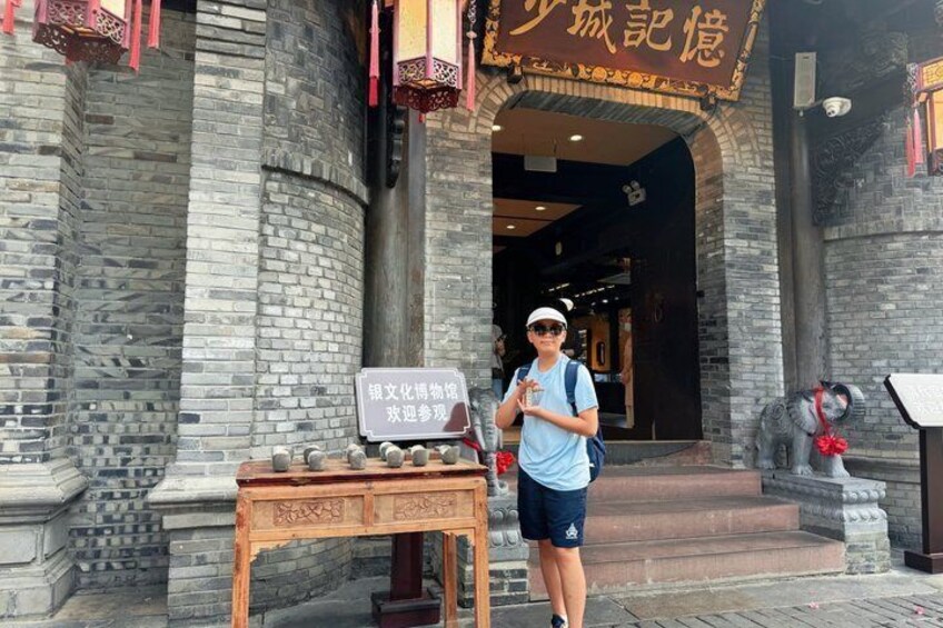 A person standing in front of a traditional building with stone architecture and a signboard. 2