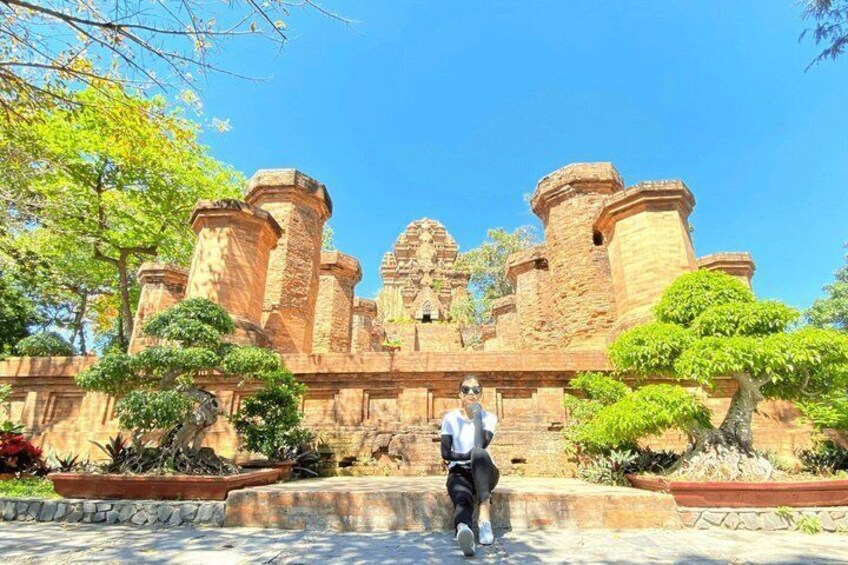 A person standing in front of a historic stone structure with towers and a central tower. 4