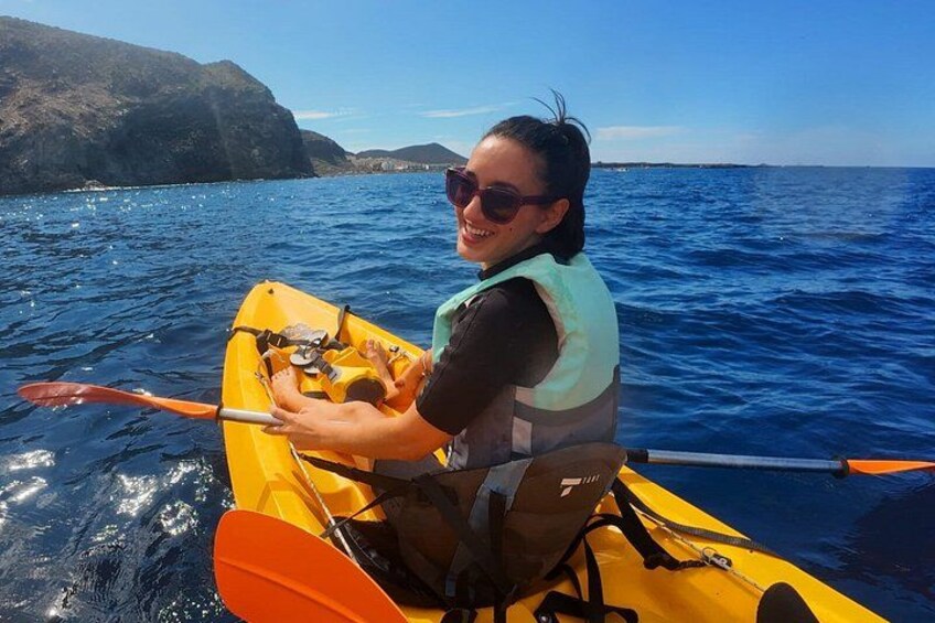 A person in a yellow kayak on a body of water with mountains in the background. 5