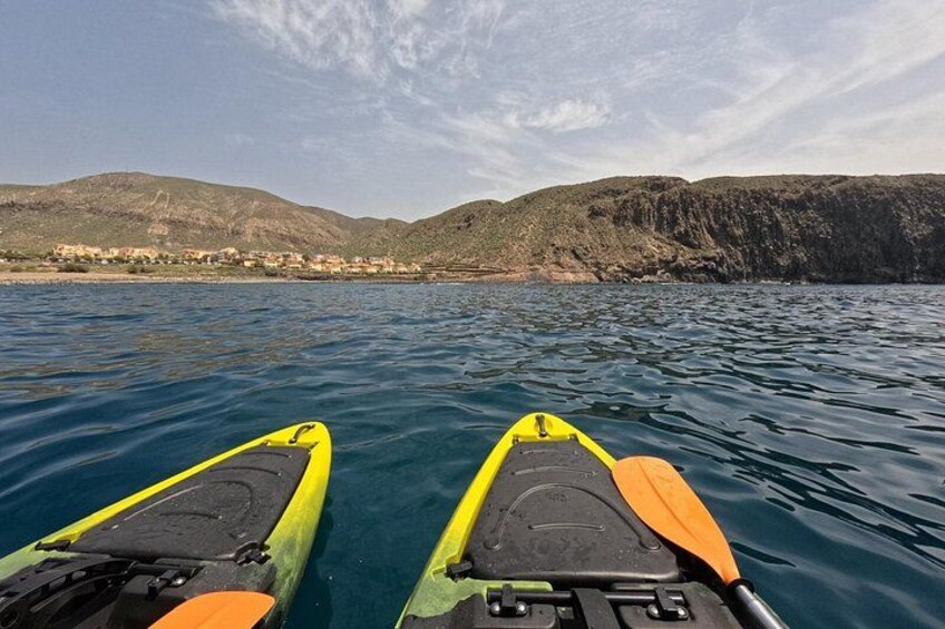 Two kayaks on calm water with a coastal landscape in the background. 3