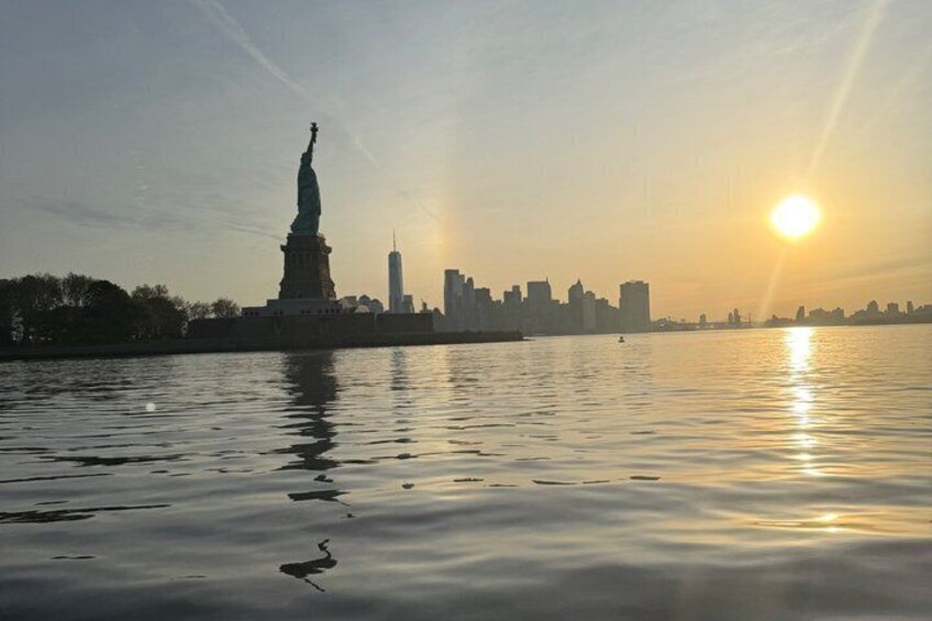 The Statue of Liberty at sunset with the city skyline in the background. 2