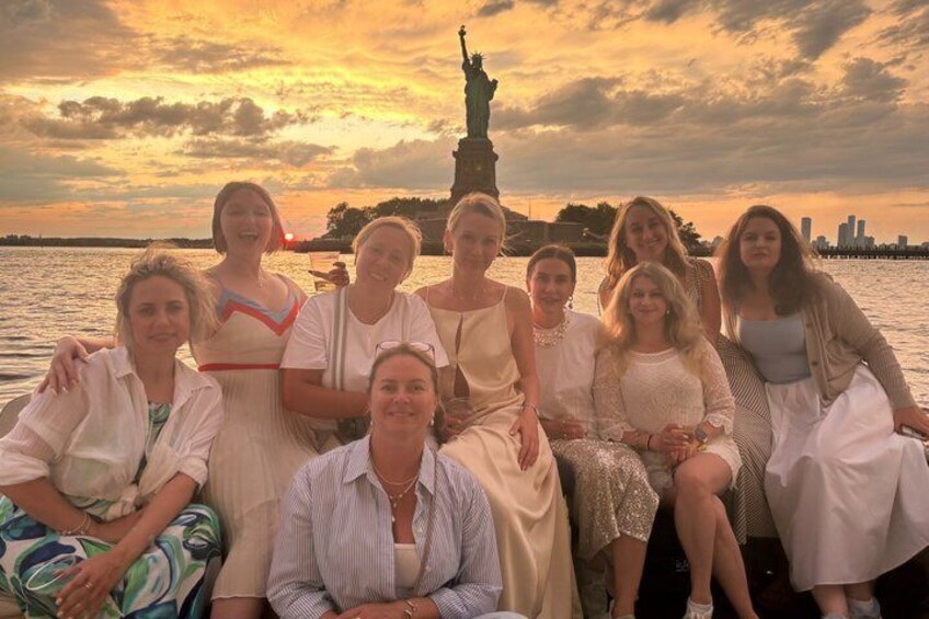 A group of people sitting by a body of water with a statue in the background. 5