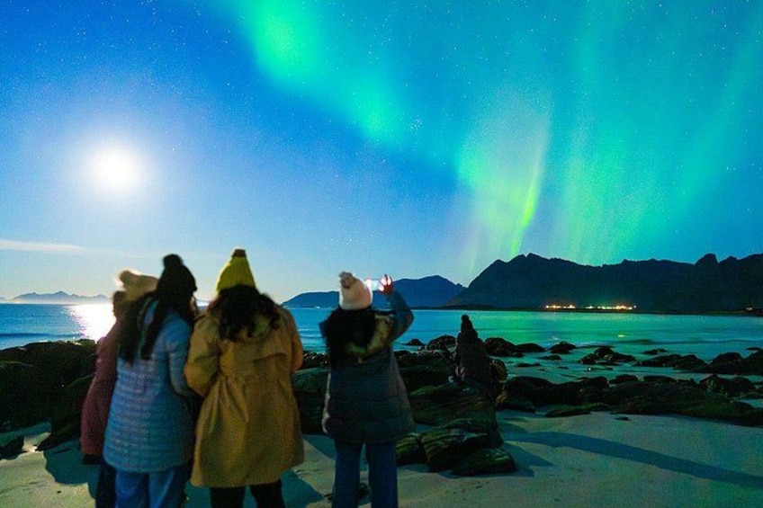 A group of people observing the Northern Lights at night. 1