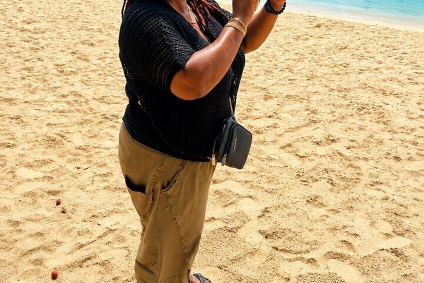A person standing on a sandy beach with a black bag. 3
