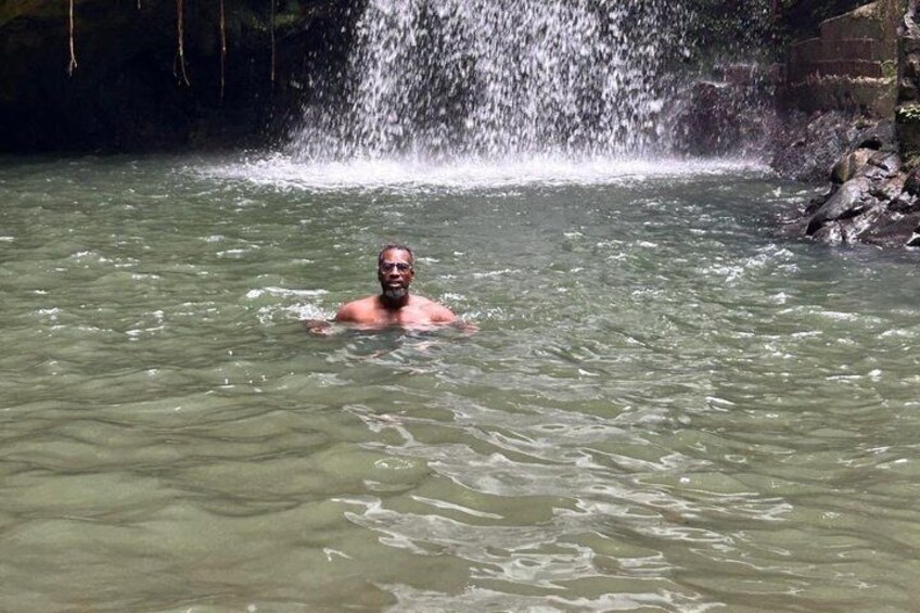 A person swimming in a natural water body with a waterfall in the background. 3