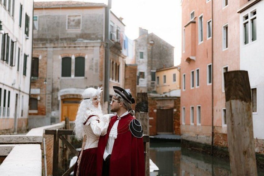 Un vicolo stretto con edifici storici, un canale e una persona in costume d'epoca. 1