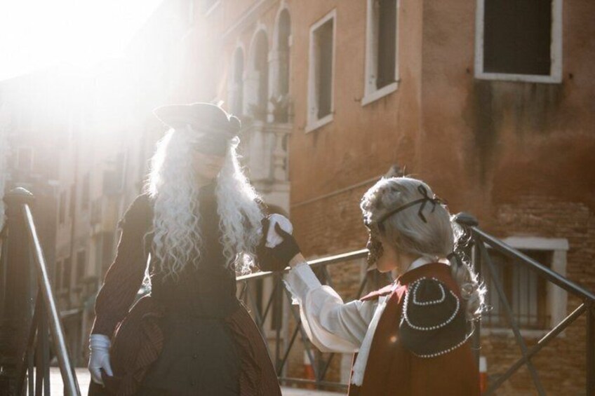 Two people in historical costumes standing on a balcony with a building in the background. 5