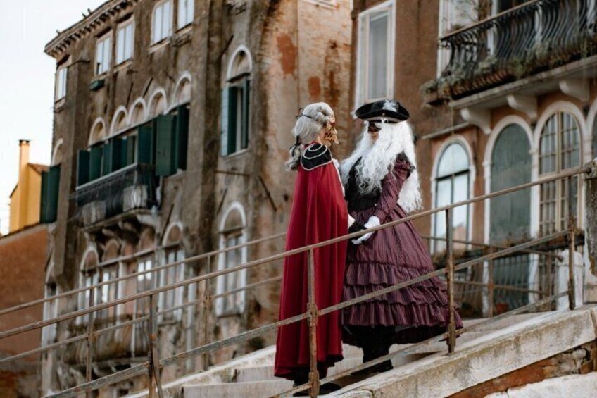 Two people in period costumes standing on a stone staircase with a historic building in the background. 3