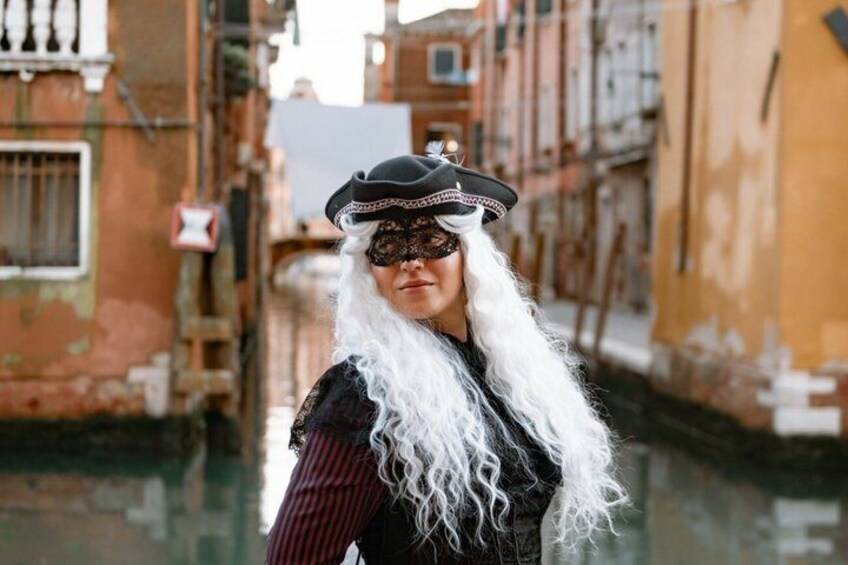 A person in historical costume standing in a narrow waterway between buildings. 4