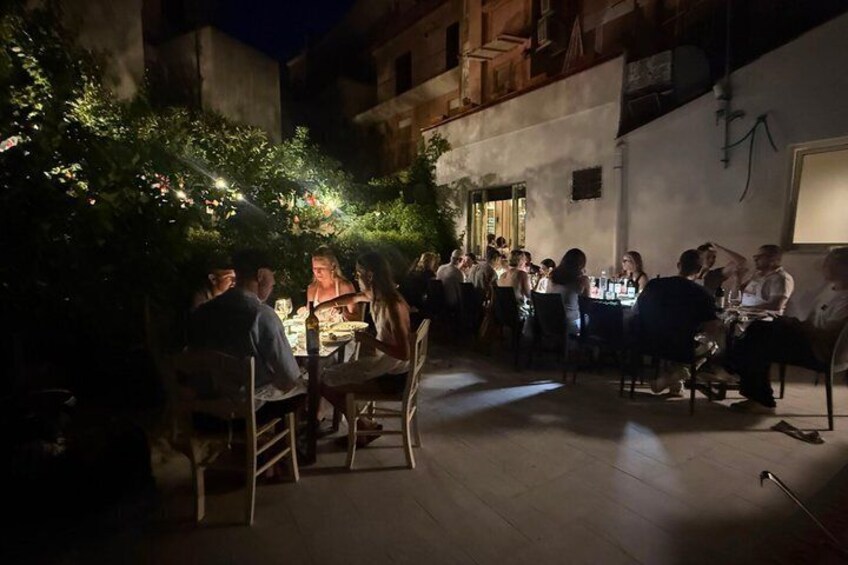 An outdoor dining area with tables and chairs, surrounded by greenery and buildings. 4