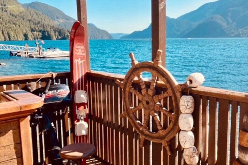 A wooden deck with a steering wheel, a red surfboard, and a fishing rod. 3