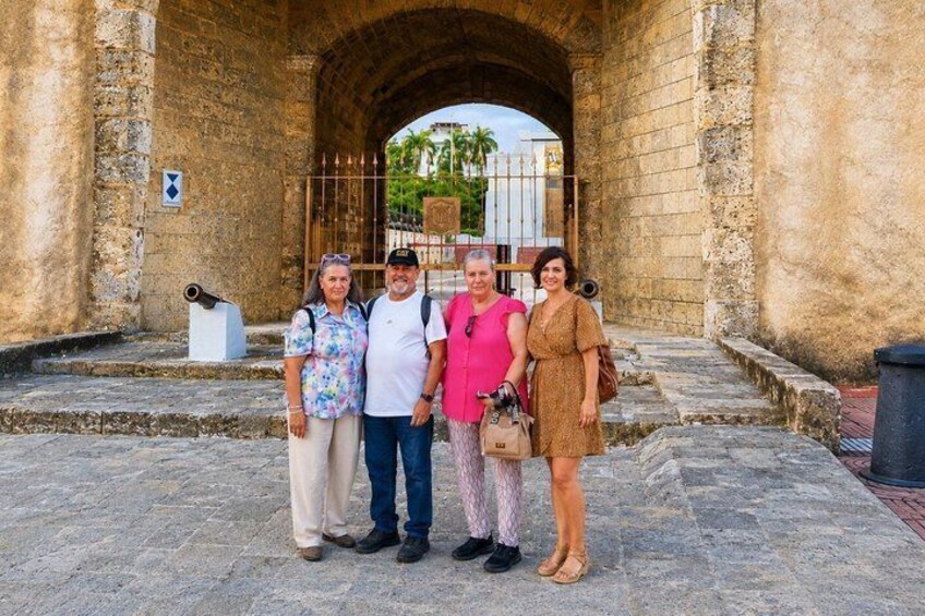 A group of people standing in front of a historic stone archway. 2