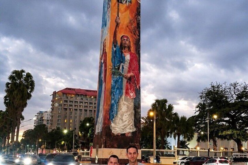 A large mural of a religious figure on a pole, with palm trees and a building in the background. 5
