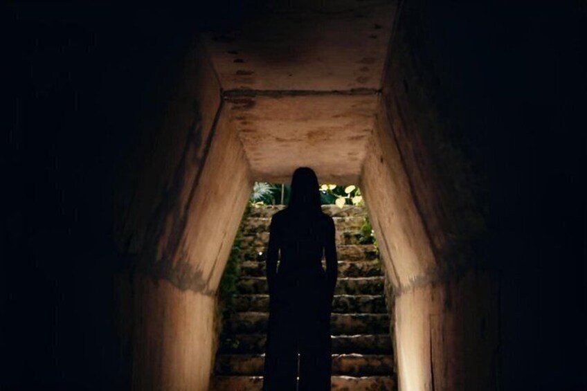 A person walking down a dimly lit stone staircase. 2