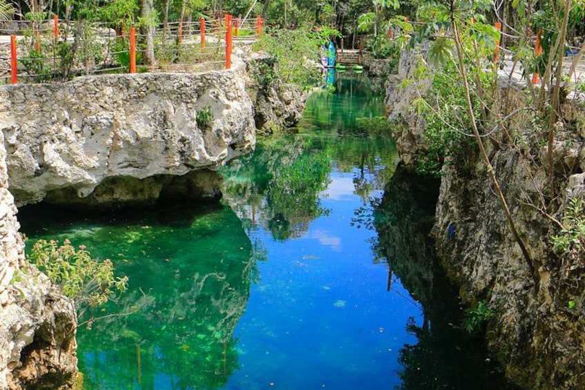 A clear blue pool surrounded by rocky terrain and greenery. 2