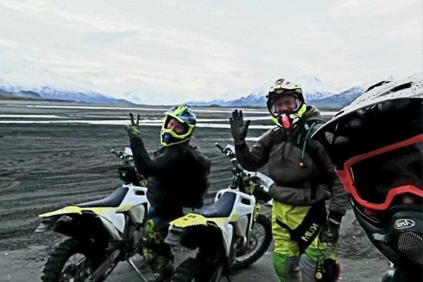 Two people on motorcycles in a barren landscape with mountains in the background. 5