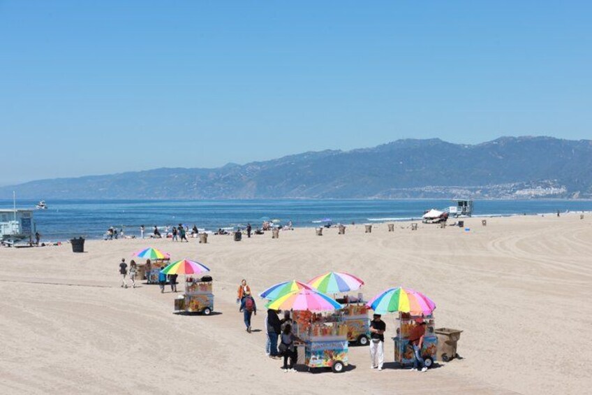 A beach with colorful umbrellas and a lifeguard tower in the background. 1