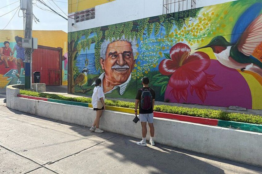 A mural with a large portrait, vibrant flowers, and a hummingbird. 5