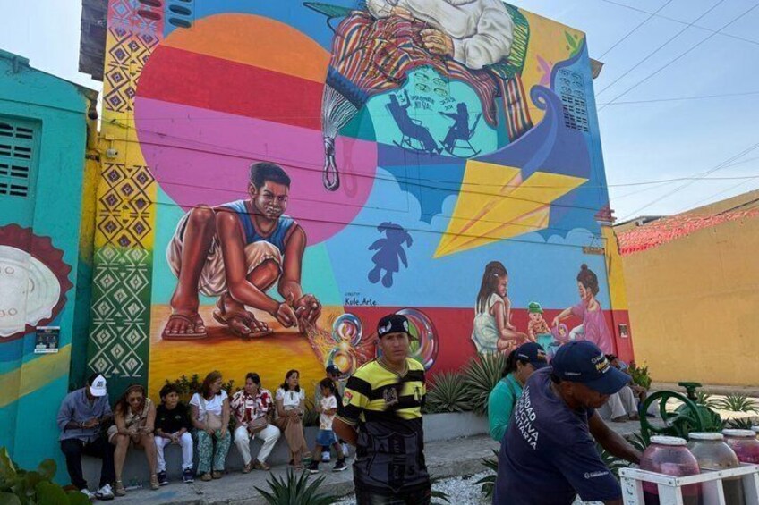 A colorful mural with a large figure and people gathered in front. 4