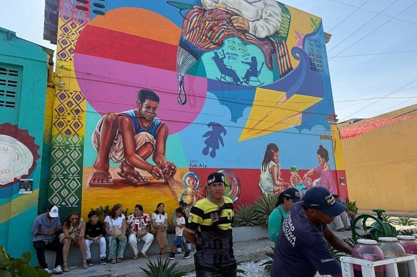 A colorful mural with a large figure and people gathered in front. 3