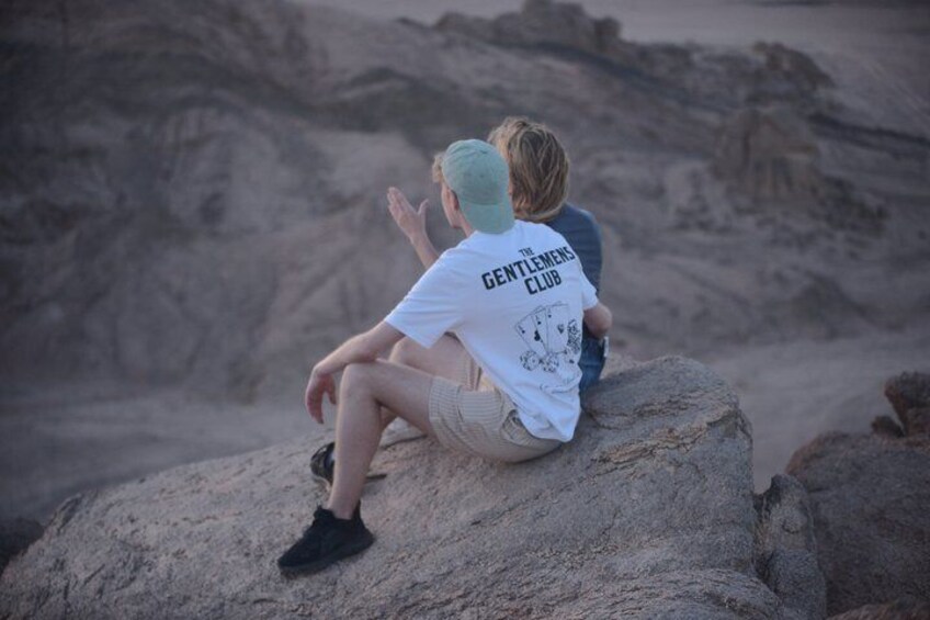 Two people sitting on a rock with a desert landscape in the background. 5