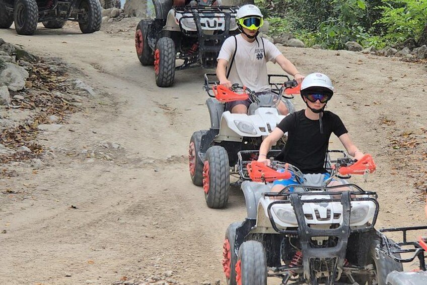 Two people riding atv's on a dirt path. 4