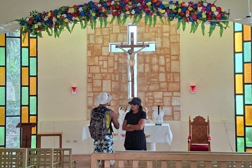 A church interior with a cross, altar, pews, and floral decorations. 4