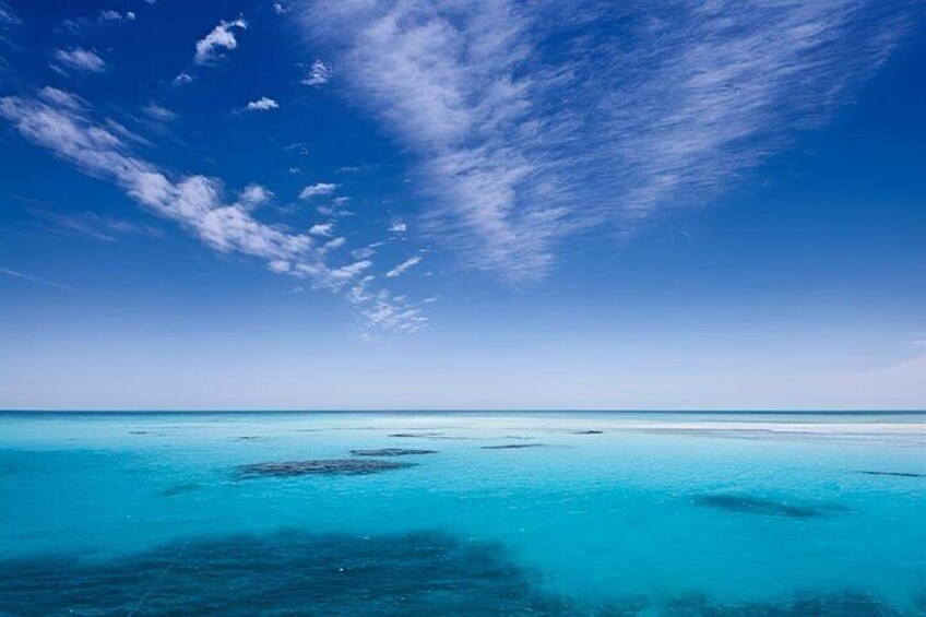 A clear blue sky, turquoise sea, and distant land. 4