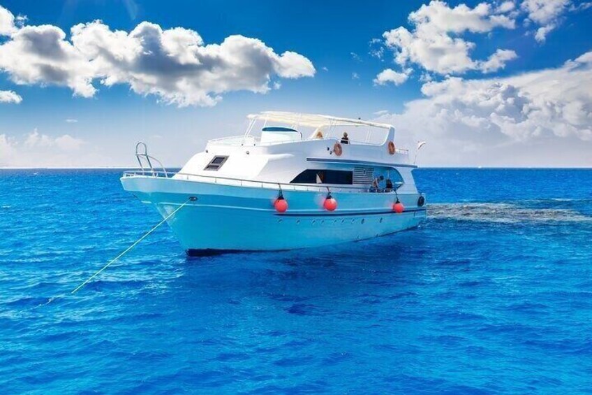 A white boat with red life rings on a clear blue sea under a partly cloudy sky. 1