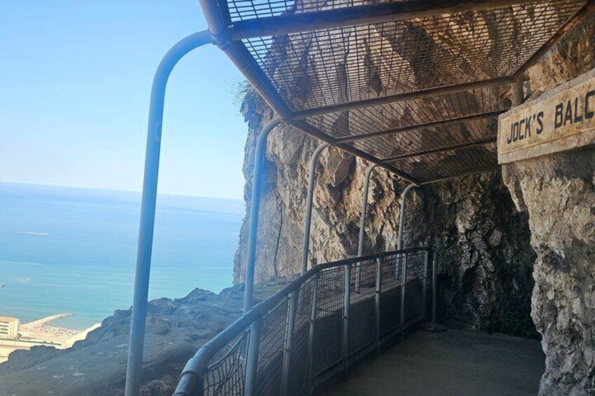 A metal staircase leading to a viewing platform with a sign reading 'JOCK'S BALCONY,' overlooking a coastal area. 5