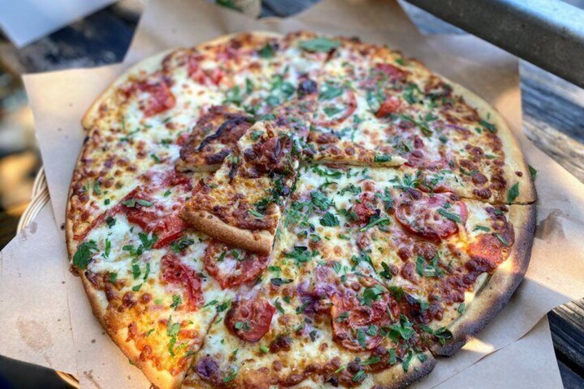 A pizza with tomato and basil toppings on a wooden surface. 1