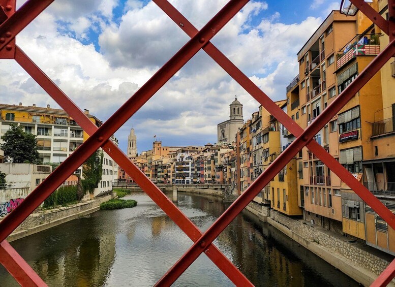 A river with buildings on both sides, a bridge in the foreground, and a tower in the background. 1