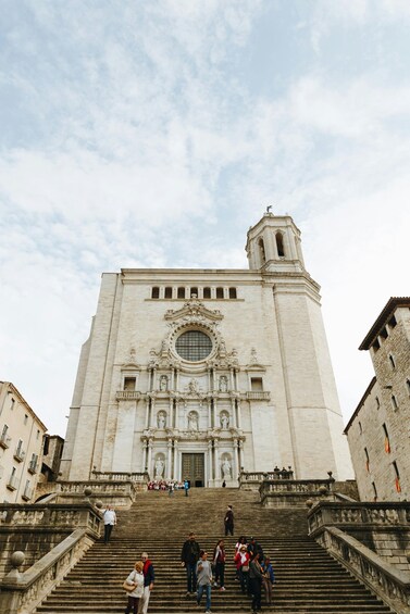 A grand historical building with a large dome and bell tower, surrounded by stone steps and a few people. 3