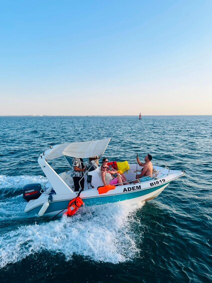 A boat with people on it, moving through the water. 1