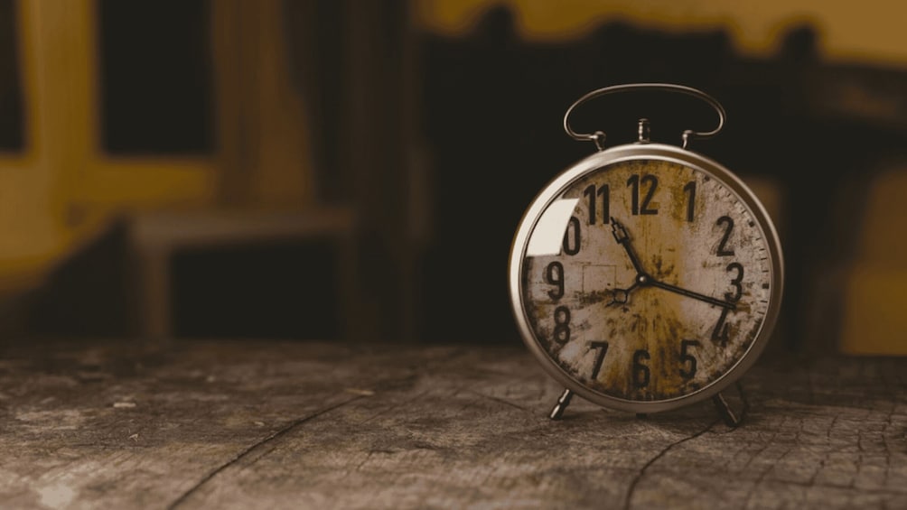 An old-fashioned alarm clock on a wooden surface. 1