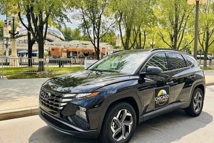 A black SUV parked on a city street with trees and buildings in the background. 5